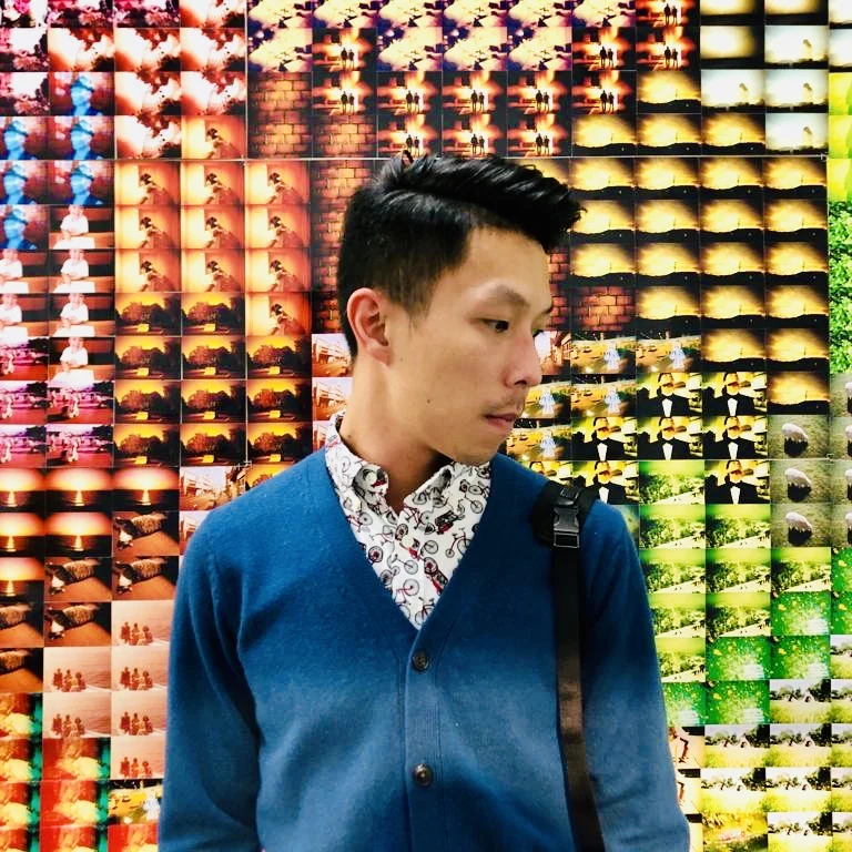 Didier in a blue cardigan in front of a wall of photographic contact sheets